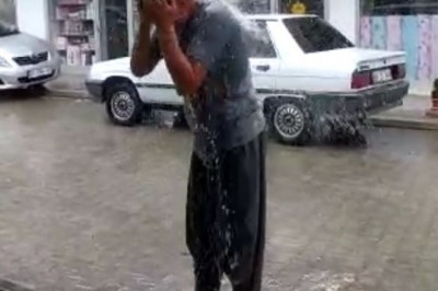 Ağustos'ta yağan yağmur altında banyo yaptı
